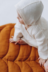 Cute studio portrait of a little newborn girl posing for a photo on a light background. A baby who has already learned to crawl and sit