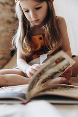 portrait of a little girl sitting on the floor and reading children's literature