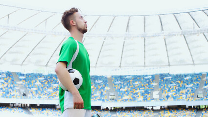 side view of young football player in green t-shirt breathing while holding ball © LIGHTFIELD STUDIOS