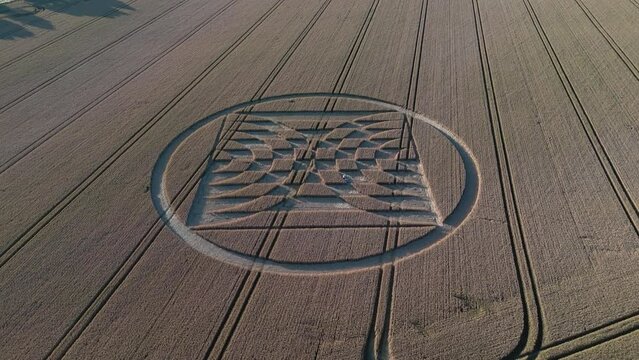 Aerial flyover view above Micheldever Station geometric alien crop circle artwork tilt up to harvest farmland countryside