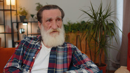 Close-up of sad sick senior old grandfather man at home looks pensive thinks over life concerns or...