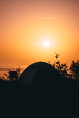Fototapeta na wymiar Piękny wschód słońca nad morzem z namiotem w tle