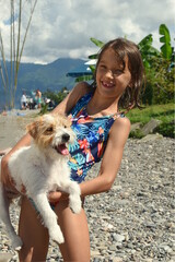 kid smile outdoors beach swimsuit hold dog holding white puppy jack russell cute tan summer sky wet hair after swimming