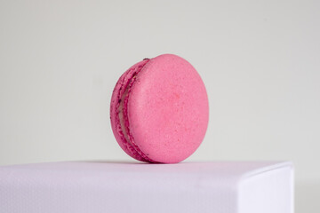 Close-up of appetizing pink macaroon on white box on light background.