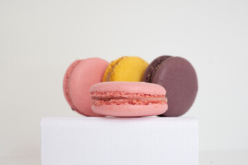 Close-up of appetizing colorful macaroons on white box on light background.