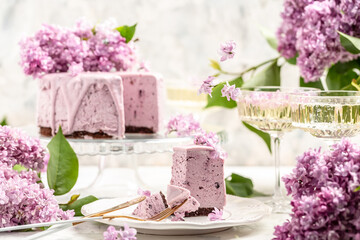 Obraz na płótnie Canvas a piece of mousse cake, Delicious dessert blueberry tart with fresh berries with a bouquet of purple blooming lilacs, place for text