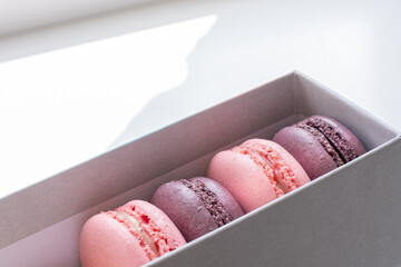 Close-up of appetizing colorful macaroons in grey box on white background.