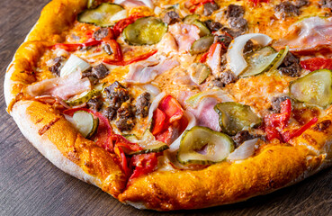 Pizza with Mozzarella cheese, Bolognese sauce, minced meat, bacon, tomato and vegetables. Italian pizza on wooden background.