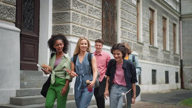 Group of happy teenagers together in front of school, back to school concept.