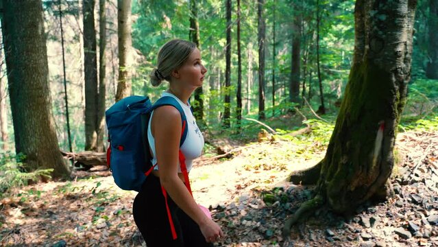 young girl hiking in the mountains in summer in the green forest