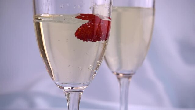 Falling strawberries in a glass of sparkling wine on