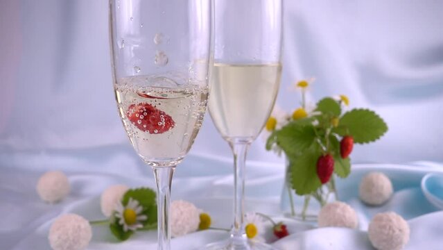 Falling strawberries in a glass. Glasses with sparkling