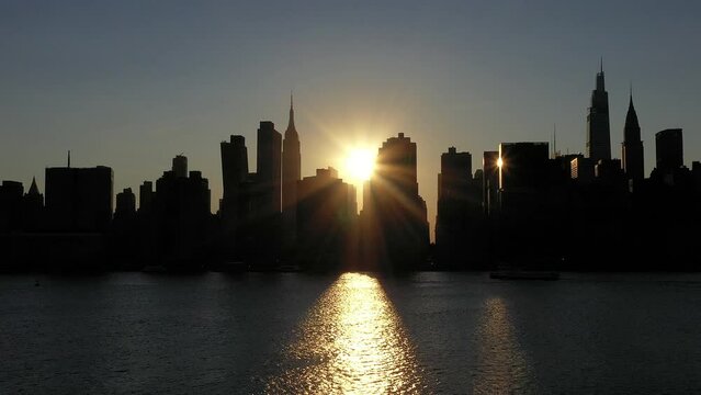 long crisp gorgeous stationary shot of the start of the rare Manhattanhenge phenomenon with an intense sunbeam from between the legendary skyline