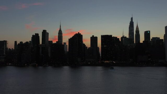 gorgeous stationary aerial shot of Midtown Manhattan at dusk with a ferry boat