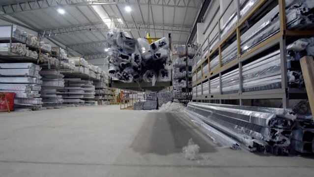 industrial crane carrying aluminum bars inside a factory and depositing them on the ground