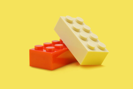 Fake lego plastic bricks red and beige in group isolated on yellow. Editorial illustrative image of popular children constructor.