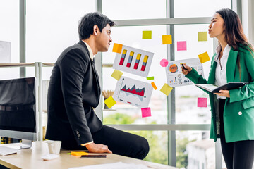 Casual creative happy two smile asian business people plan strategy analysis and brainstorm putting post it sticker note to share idea for startup project on glass board at modern office