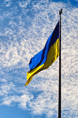 The Biggest National flag Ukraine against blue sky with fantastic soft clouds. Blue and yellow flag of Ukraine. Waving Ukrainian flag.  Portrait orientation