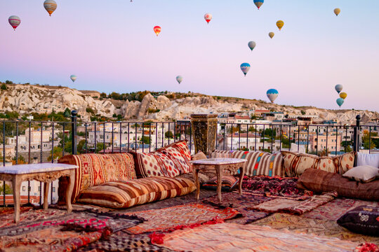 terrace of hotel in Goreme Cappadocia and hot air balloons rising into sky, concept  of must see travel destination, bucket list trip