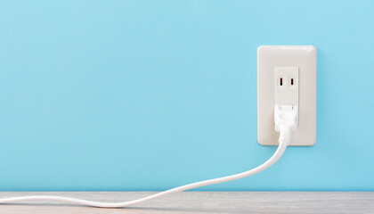 white electric outlet mounted on light blue wall. 水色の壁に取り付けられた白いコンセント	