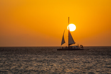 Idyllic beach with sailboat in Aruba at golden sunset, Dutch Antilles