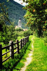 Fototapeta na wymiar Riverside path to church of San Pancrazio beside the Mediaeval walled town of Stadt Glurns, Glorenza. Val Venosta, Italian Alps