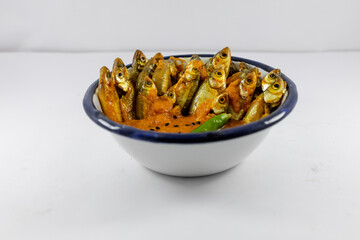 Mourala fish or indian carplet fish cooked in yellow gravy in white ceramic bowl on white background. selective focus