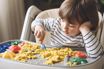 Cute little boy playing with kinetic sand. Development of fine motor skills. Early sensory education. Activities Montessori. Sensory plays at home.