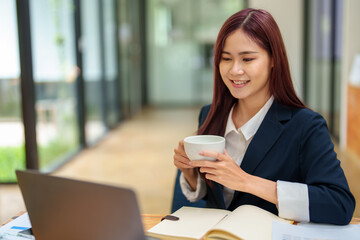 Fototapeta na wymiar Asian female worker using computer and budget documents on desk