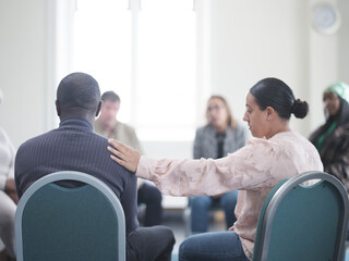 Woman consoling man in group therapy session