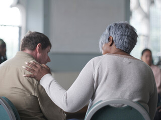 Woman consoling man in group therapy session