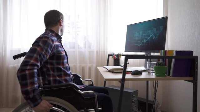 A disabled worker sitting in a wheelchair works at a computer