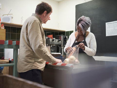 Volunteer Giving Man Vegetables In Community Food Center