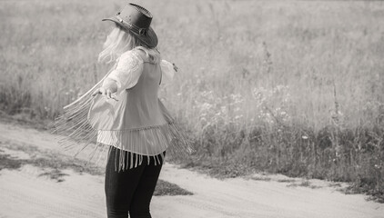 Woman Plus size in American country style black boho jacket, with a fringe, shirt and cowboy hat at nature