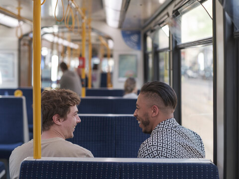 UK, South Yorkshire, Smiling gay couple talking in tram