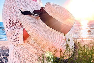 woman  straw hat in  woman hand at  summer sea beach  sun light flares 