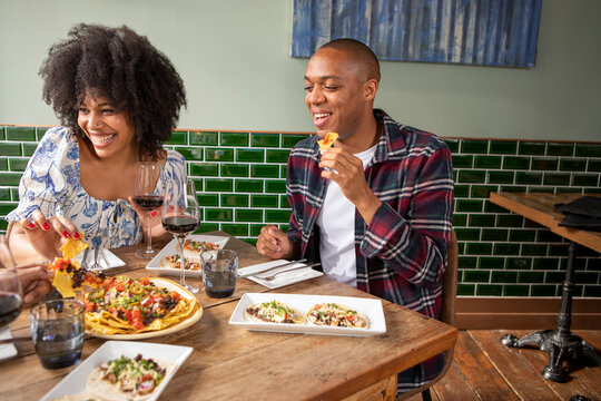 UK, London, Smiling Friends Enjoying Mexican Food At Restaurant Table