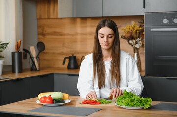 Beautiful young woman is preparing vegetable salad in the kitchen. Healthy Food. Vegan Salad. Diet. Dieting Concept. Healthy Lifestyle. Cooking At Home.