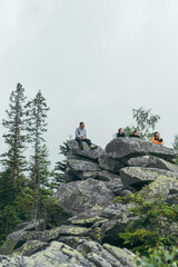 A group of friends hikers sit on a rock in the mountains and rest during a hike. Vertical