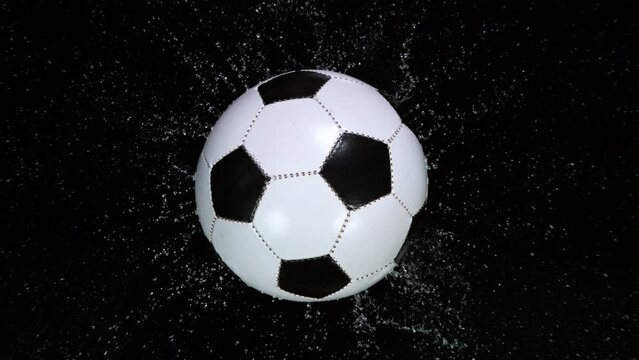Close-up of Falling Soccer Ball on Water Black Surface. Super Slow Motion at 1000 fps. Filmed on High Speed Cinematic Camera.