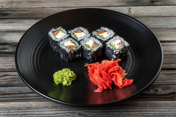 Close-up of fresh rolls and sushi set, with salmon, sprinkled with black caviar. Plate in the middle of the composition