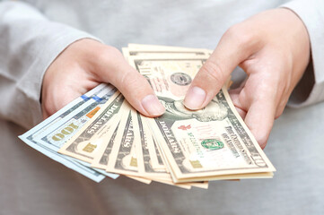 Different dollar bills in hands close-up. - obrazy, fototapety, plakaty