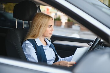 Fashion business woman with financial papers by her car