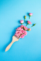 Paintbrush with pink roses on the blue background. Top view. Location vertical.