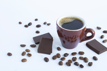 Black coffee in the brown cup, coffee beans and pieces of chocolate on the white  background....