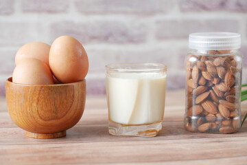 eggs in a bow, almond nuts and a glass of milk on table 