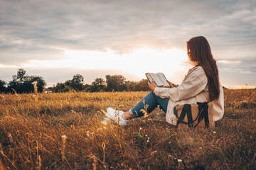 Christian woman holds bible in her hands. Reading the Holy Bible in a field during beautiful...