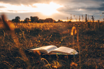 Open bible on the field at sunset