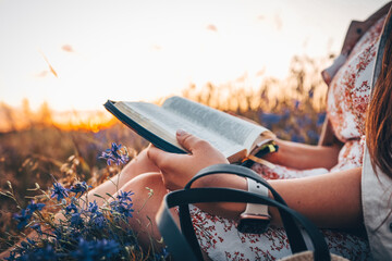 Christian woman holds bible in her hands. Reading the Holy Bible in a field during beautiful sunset. Concept for faith, spirituality and religion. Peace, hope
