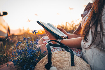 Christian woman holds bible in her hands. Reading the Holy Bible in a field during beautiful sunset. Concept for faith, spirituality and religion. Peace, hope